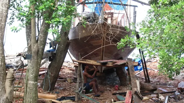 Traditional wooden boat under construction in Labuan Aji village